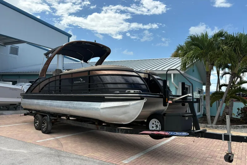 The Image of 2019 Bennington 25 QSBA pontoon boat on trailer, parked near palm trees. - 1