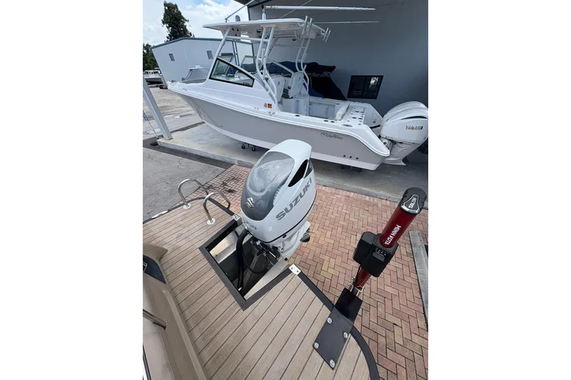 Slide: The Image of 2019 Bennington 25 QSBA boat with Suzuki outboard motor and Yamaha engine in marina setting. - 15