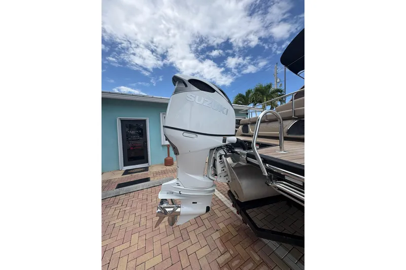 Slide: The Image of 2019 Bennington 25 QSBA boat with Suzuki outboard motor, parked on brick driveway. - 20