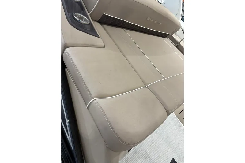 Slide: The Image of 2019 Bennington 25 QSBA boat with beige cushioned seating and cup holders. - 28