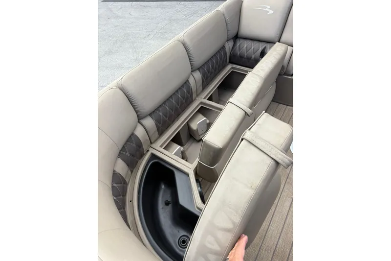 Slide: The Image of 2019 Bennington 25 QSBA boat interior with open storage compartments and beige seating. - 4