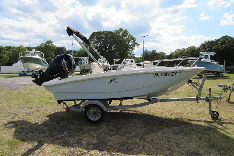 Slide: The Image of 2021 Boston Whaler 130 Super Sport boat on trailer, parked on grass. - 2