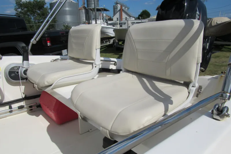 Slide: The Image of 2021 Boston Whaler 130 Super Sport interior with seating and console, parked on grass. - 7