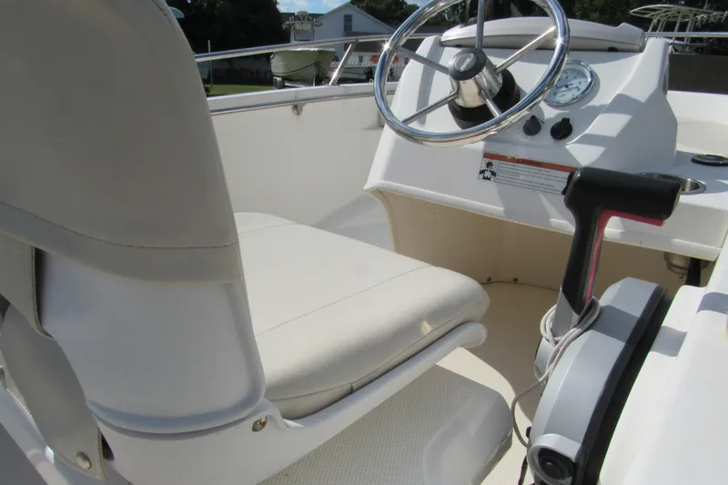 Slide: The Image of 2021 Boston Whaler 130 Super Sport boat interior with white cushioned seats. - 8