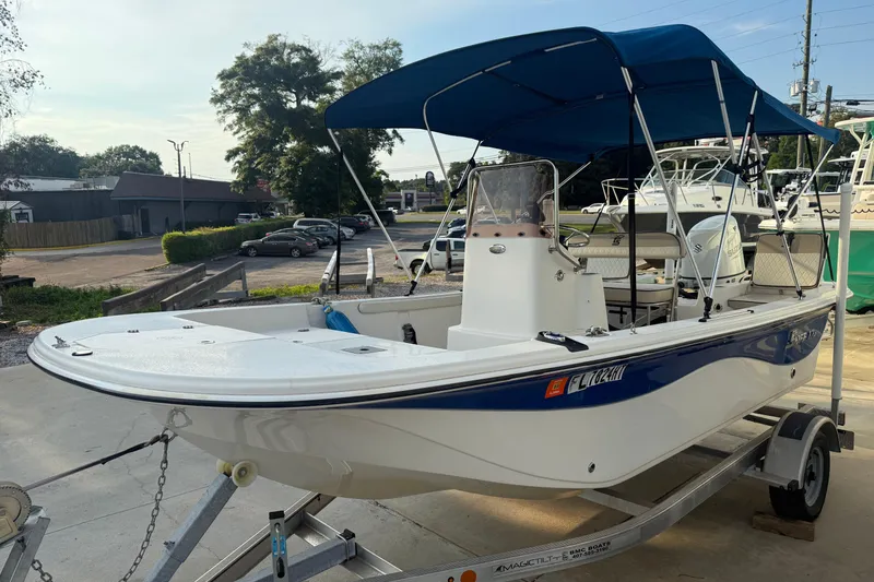 The Image of 2022 Carolina Skiff 17 LS boat with blue canopy on a trailer in a parking lot. - 1