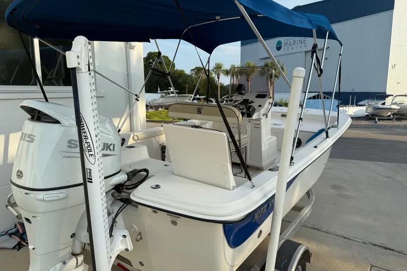 Slide: The Image of 2022 Carolina Skiff 17 LS boat with Suzuki engine and blue canopy at a marine center. - 3