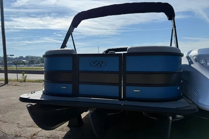 Slide: The Image of 2025 Bentley Pontoons Legacy 243 Navigator, blue and black design, parked outdoors under clear sky. - 2