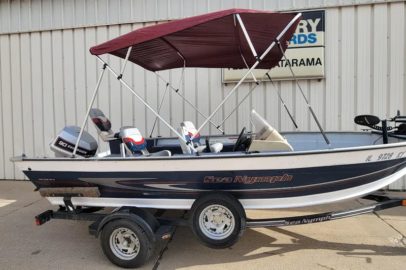 Slide: The Image of 1997 Sea Nymph 168 DLX boat with maroon canopy on trailer, parked outside. - 27