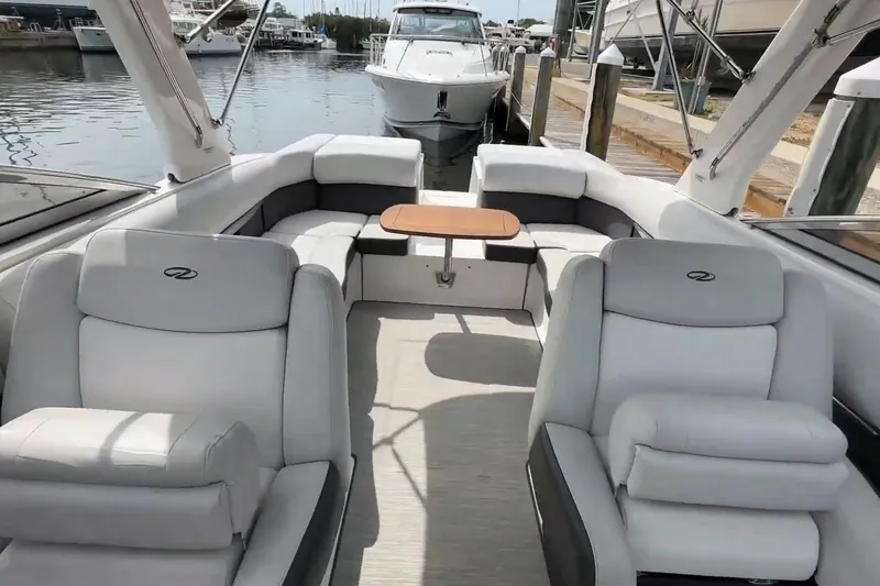 Slide: The Image of 2016 Regal 2700 ES Bowrider interior with plush seating and table, docked at marina. - 8