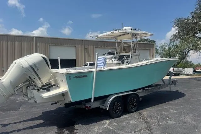 Slide: The Image of 1992 Mako 261B boat on trailer, parked outdoors near industrial building. - 2