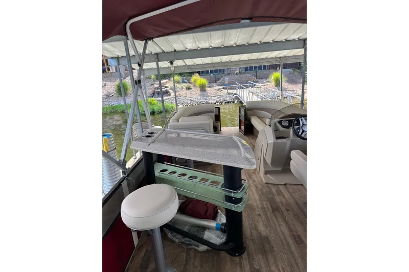 Slide: The Image of 2017 Crest II 250 SLE pontoon boat interior with seating and helm, docked by the shore. - 9