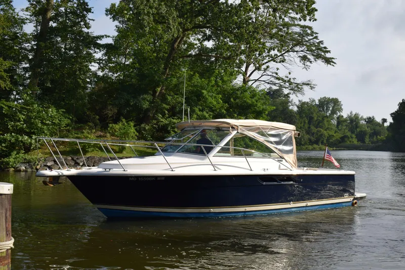 Slide: The Image of 2002 Tiara 2900 Coronet boat on a serene river, surrounded by lush greenery. - 0