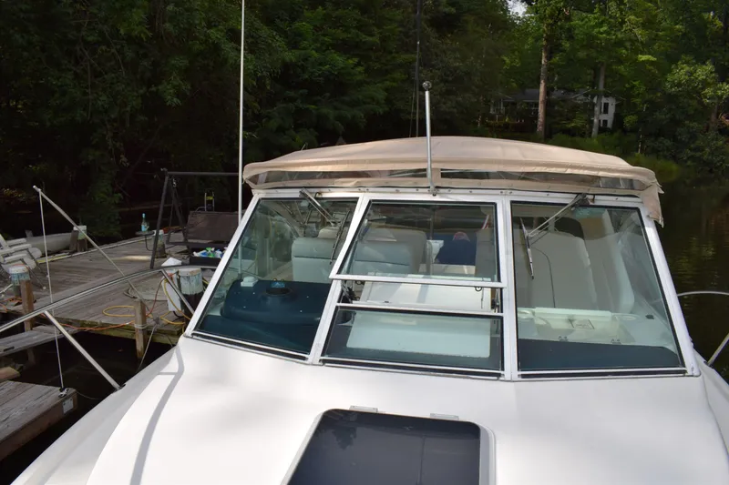 Slide: The Image of 2002 Tiara 2900 Coronet boat docked by a lush, green shoreline. - 2