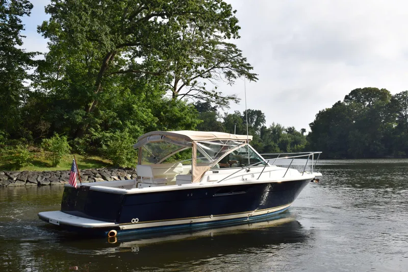 Slide: The Image of 2002 Tiara 2900 Coronet boat cruising on a serene river with lush greenery. - 26