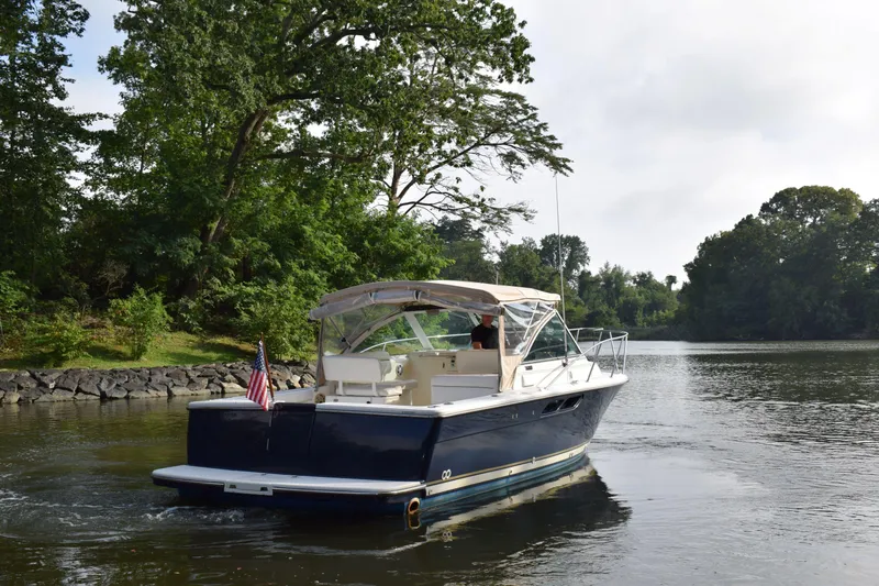 Slide: The Image of 2002 Tiara 2900 Coronet boat cruising on a serene river with lush greenery. - 27