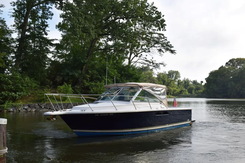 Slide: The Image of 2002 Tiara 2900 Coronet boat cruising on a serene river with lush greenery. - 28
