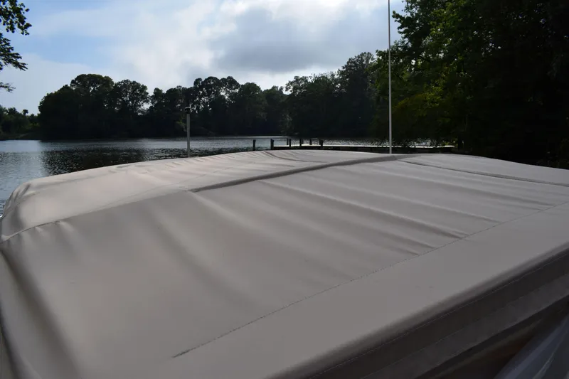 Slide: The Image of Covered Tiara 2900 Coronet boat docked by a serene lake, surrounded by trees. - 3