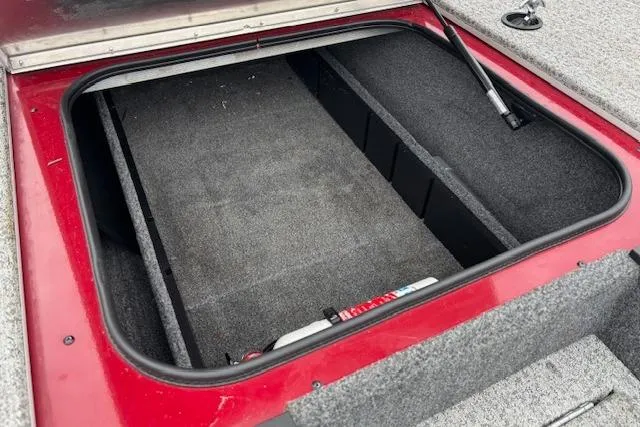 Slide: The Image of Open storage compartment of 2023 Tracker Pro Team 175 TXW boat, featuring red and gray interior. - 16