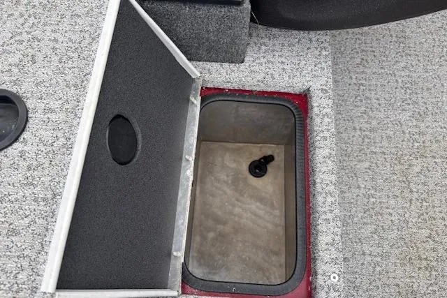 Slide: The Image of 2023 Tracker Pro Team 175 TXW storage compartment with open lid on carpeted floor. - 17