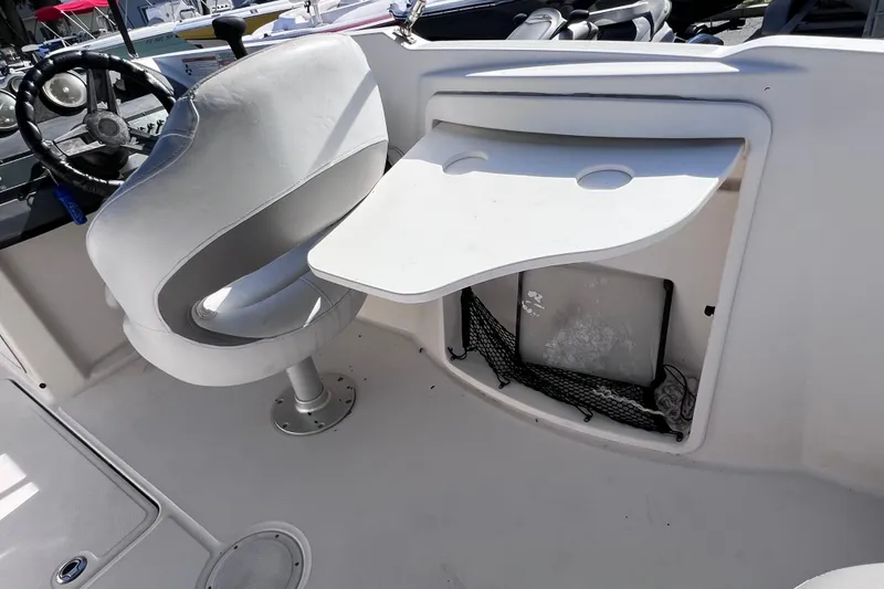Slide: The Image of 2018 Bayliner 210 Deck Boat interior with captain's chair and foldable table. - 14