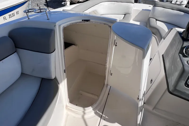 Slide: The Image of 2018 Bayliner 210 Deck Boat interior with open storage compartment and cushioned seating. - 20