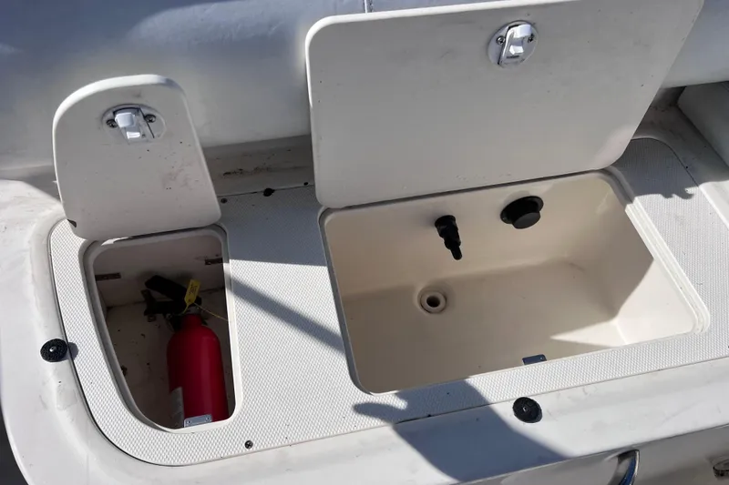 Slide: The Image of Open storage compartments on a 2018 Bayliner 210 Deck Boat, featuring a fire extinguisher. - 23