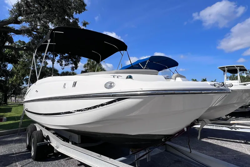 Slide: The Image of 2018 Bayliner 210 Deck Boat on trailer, under blue sky and trees. - 6