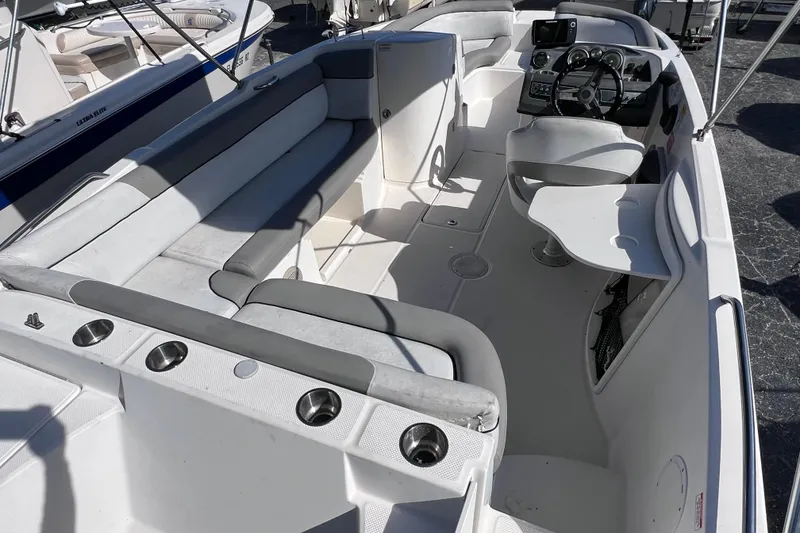 Slide: The Image of 2018 Bayliner 210 Deck Boat interior with seating, steering console, and cup holders. - 8