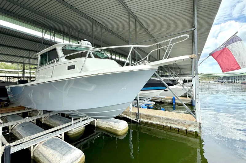 Slide: The Image of 2023 Parker 2820 XLD Sport Cabin boat docked in a marina under a metal roof. - 11