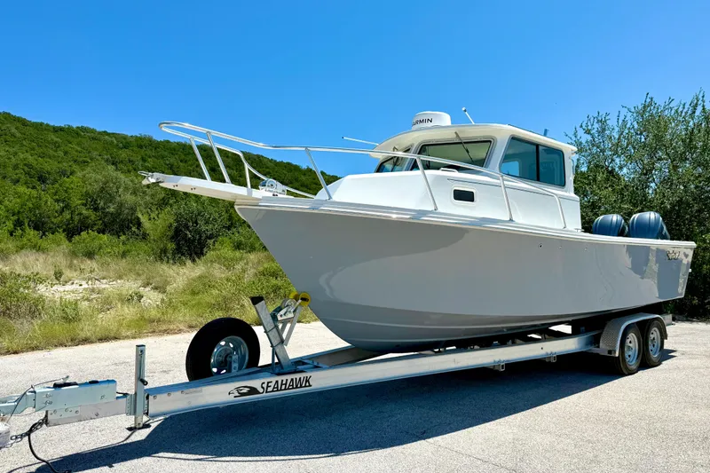 Slide: The Image of 2023 Parker 2820 XLD Sport Cabin boat on trailer, outdoors under clear blue sky. - 16