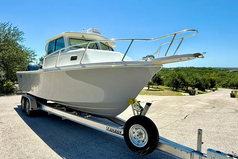 Slide: The Image of 2023 Parker 2820 XLD Sport Cabin boat on trailer, parked outdoors under clear blue sky. - 22