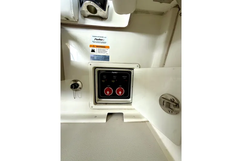 Slide: The Image of Control panel inside 2023 Parker 2820 XLD Sport Cabin boat, featuring warning labels and switches. - 31