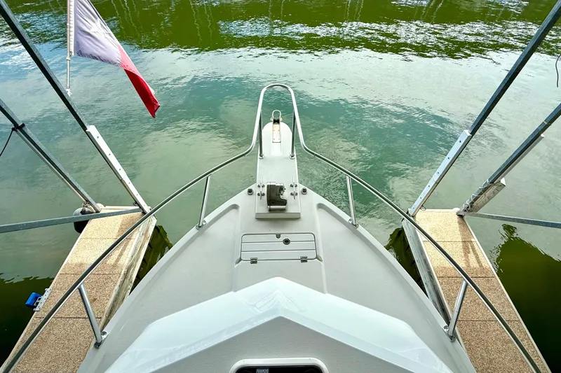Slide: The Image of 2023 Parker 2820 XLD Sport Cabin boat docked, viewed from the bow, with water and flag. - 38