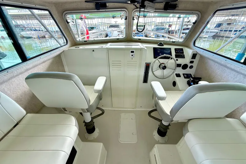 Slide: The Image of 2023 Parker 2820 XLD Sport Cabin interior with helm, seating, and windows overlooking marina. - 41