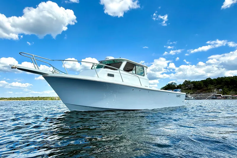 Slide: The Image of 2023 Parker 2820 XLD Sport Cabin boat on a sunny day, blue sky, and calm water. - 6