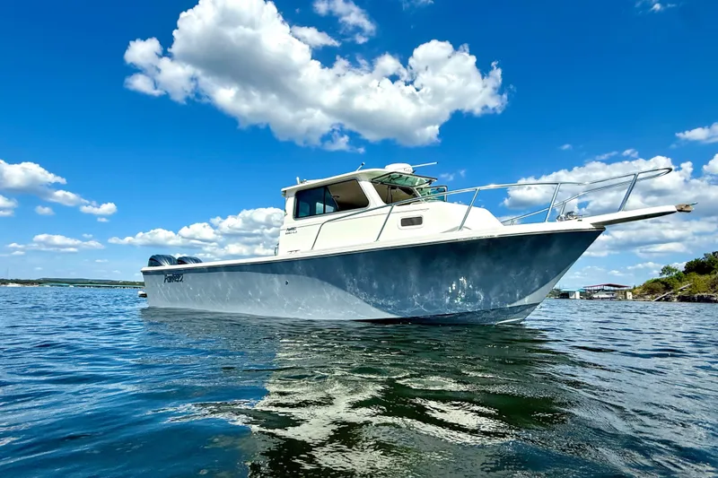 Slide: The Image of 2023 Parker 2820 XLD Sport Cabin boat on calm water under blue sky. - 8