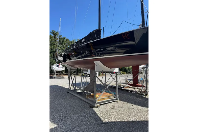 Slide: The Image of 2019 J Boats J/121 sailboat on a stand in a boatyard under clear blue sky. - 32