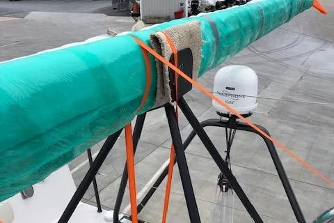 Slide: The Image of 2019 J Boats J/121 sailboat mast wrapped in green protective cover at a marina. - 37