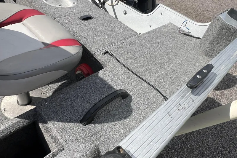 Slide: The Image of 2011 Alumacraft Classic 165 CS boat interior with gray carpet and red-accented seat. - 22