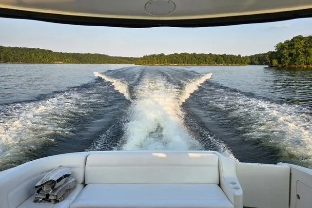 Slide: The Image of 2004 Sea Ray 460 Sundancer cruising on a serene lake, leaving a wake trail. - 18