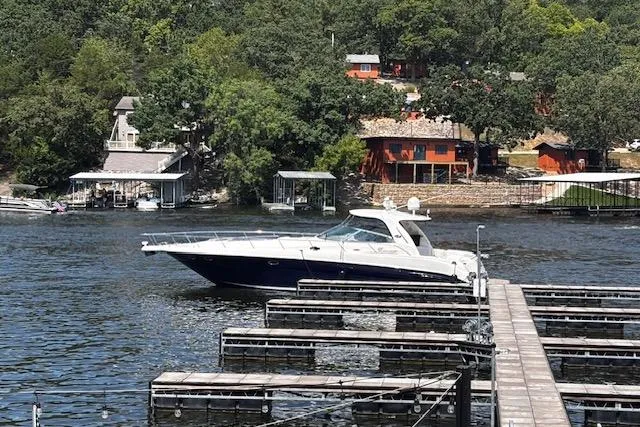 Slide: The Image of 2004 Sea Ray 460 Sundancer yacht docked on a scenic lake with lush greenery. - 4