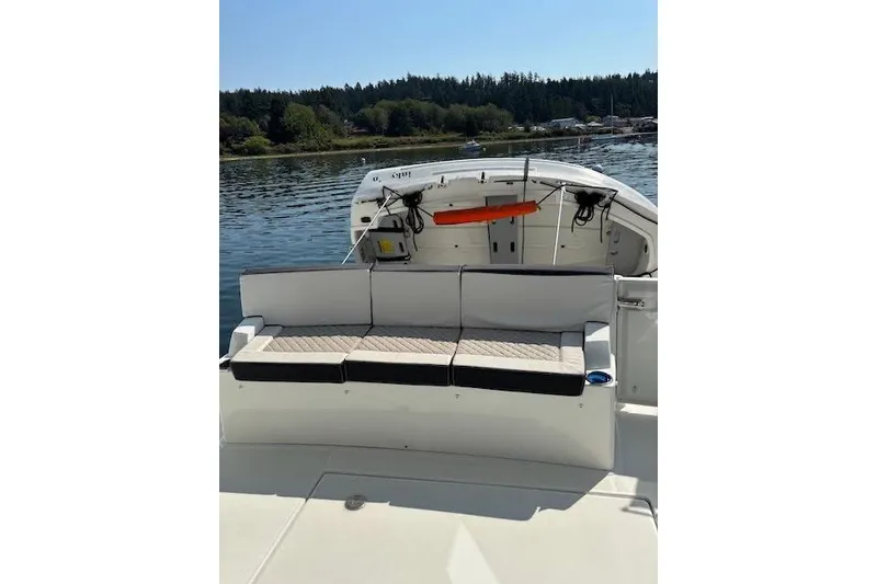 Slide: The Image of 2019 Jeanneau Velasco 37F boat with cushioned seating, docked on a serene lake. - 11