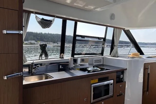 Slide: The Image of Interior of 2019 Jeanneau Velasco 37F yacht with modern kitchen and scenic window view. - 22