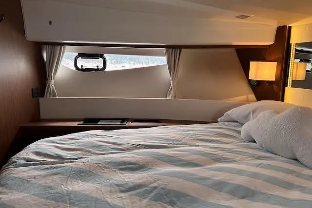 Slide: The Image of Cozy cabin interior of 2019 Jeanneau Velasco 37F with striped bedding and window view. - 28