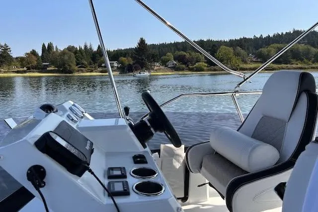 Slide: The Image of 2019 Jeanneau Velasco 37F boat helm with scenic lake view and lush shoreline. - 34