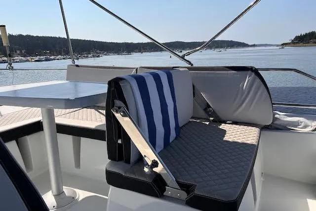 Slide: The Image of 2019 Jeanneau Velasco 37F boat interior with cushioned seating and table, overlooking serene water. - 42