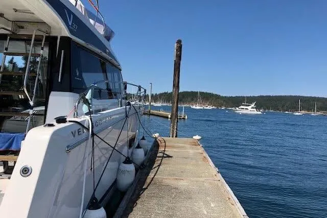 Slide: The Image of 2019 Jeanneau Velasco 37F yacht docked at a serene marina under clear blue skies. - 6