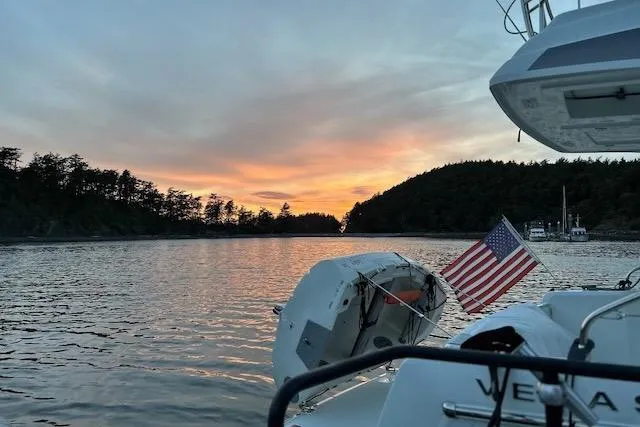 Slide: The Image of 2019 Jeanneau Velasco 37F at sunset on tranquil waters with American flag. - 9
