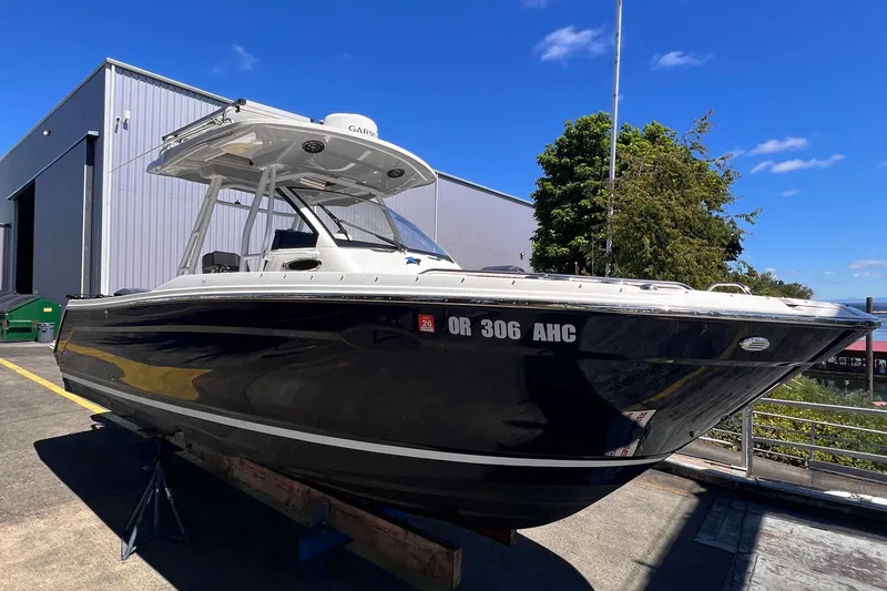 The Image of 2021 Cutwater C-24 CW boat on display outside a warehouse under a clear blue sky. - 0
