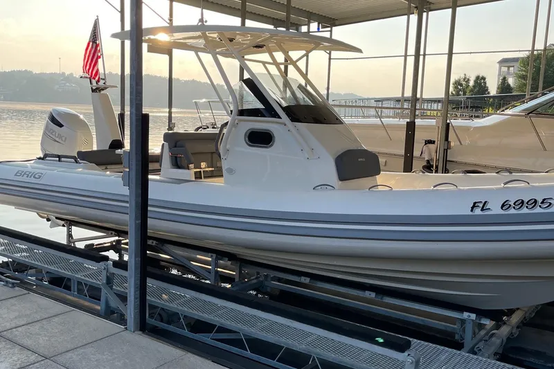 Slide: The Image of 2022 Brig Eagle 8 boat docked with American flag, Suzuki engine, and scenic waterfront view. - 1